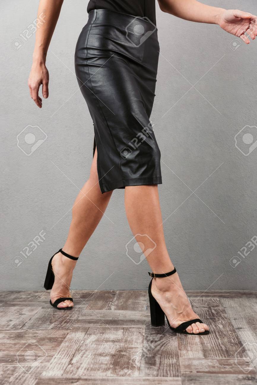 Leggy temptress in short skirt walking on the sidewalk